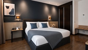 A modern hotel room with a large bed, two bedside tables, a headboard, and a dark wall with a framed artwork. - Crowne Plaza Madrid Airport by IHG (Madrid)