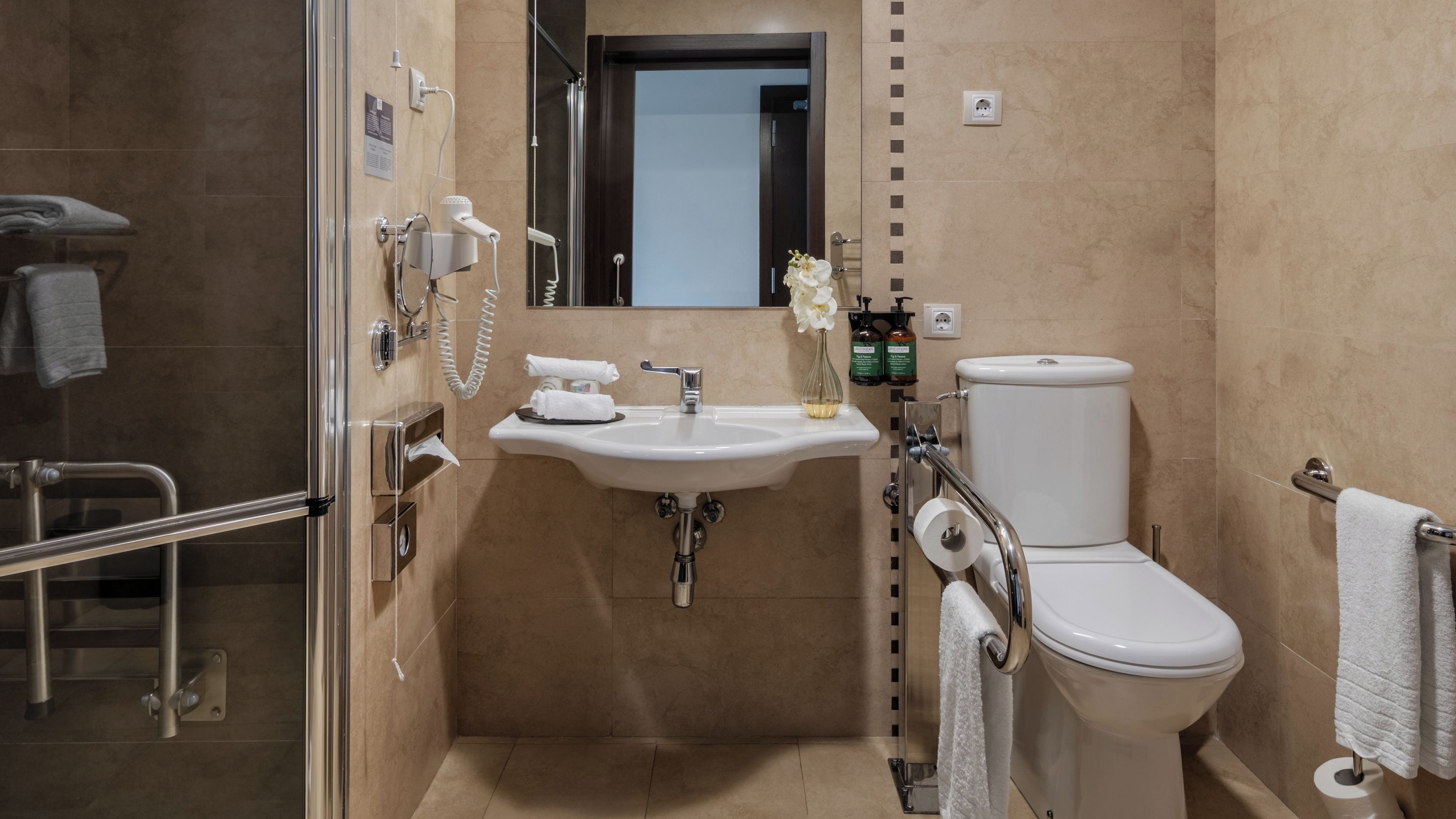 Een moderne badkamer met een douchecabine van glas, een wit wastafelmeubel met spiegel erboven en een toilet.