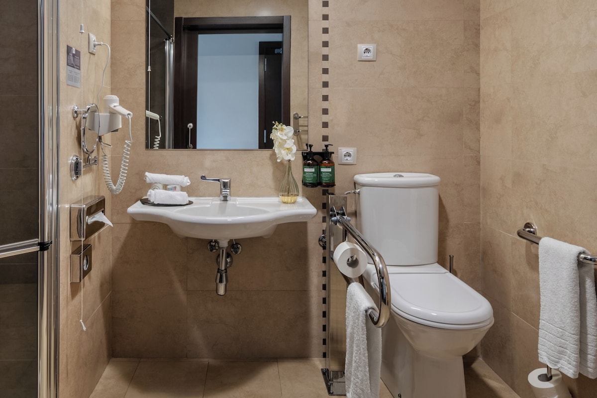 A modern bathroom with a glass shower enclosure, a white sink with a mirror above it, and a toilet.