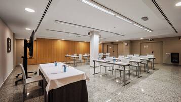 Una sala conferenze con tavoli, sedie e uno schermo per proiezioni.