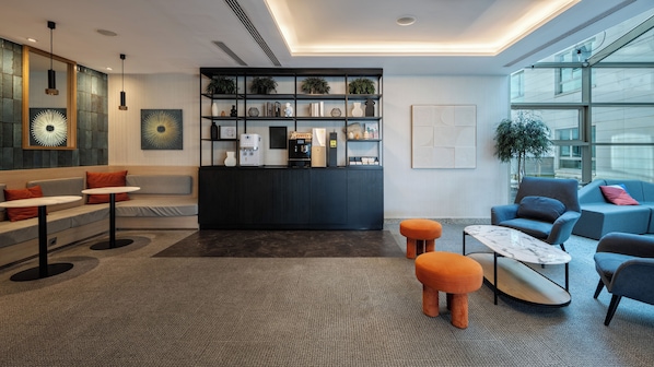 Un espace détente moderne avec des sièges, un coin café et une bibliothèque.