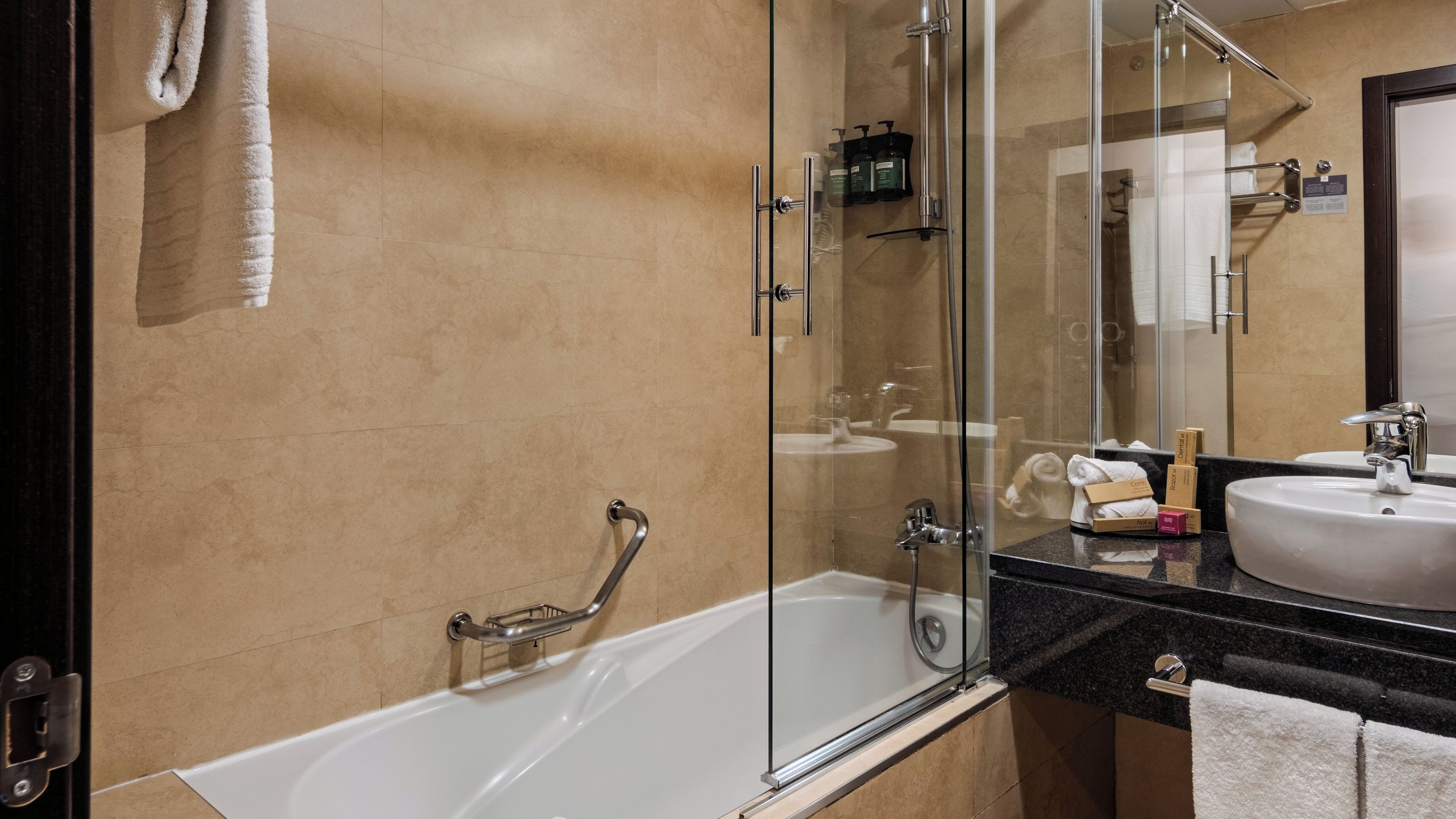 Een moderne badkamer met een douchecabine van glas, een witte badkuip, een wastafelmeubel en een spiegel.
