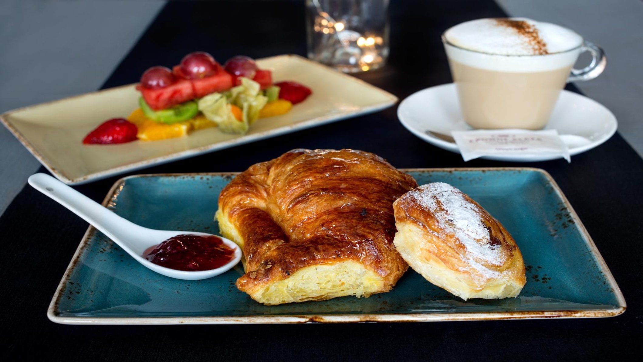 A table with a croissant, a pastry, and a cup of coffee.