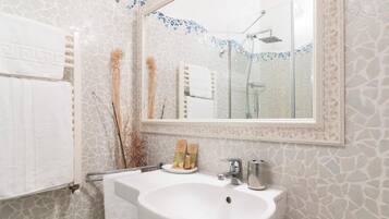 Un baño con lavamanos blanco, un espejo y una ducha.