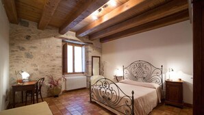 Ein Schlafzimmer mit einer Steinwand, einem Bett mit aufwendigem Metall-Kopfteil, einer Holzzahl und einem gefliesten Boden.