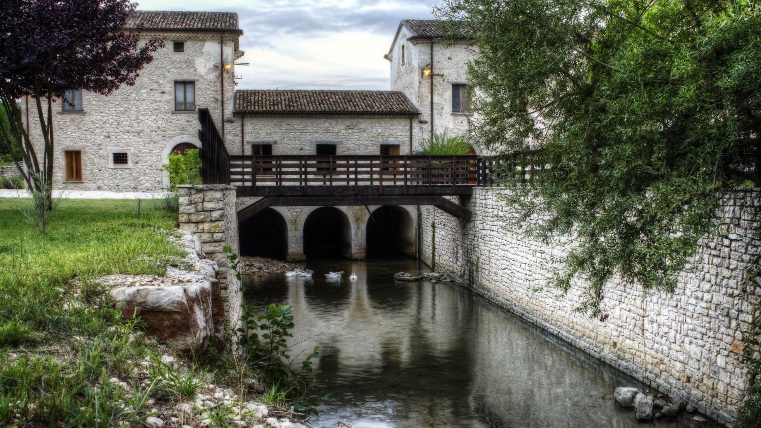 A stone bridge over a canal with two-story buildings on either side.