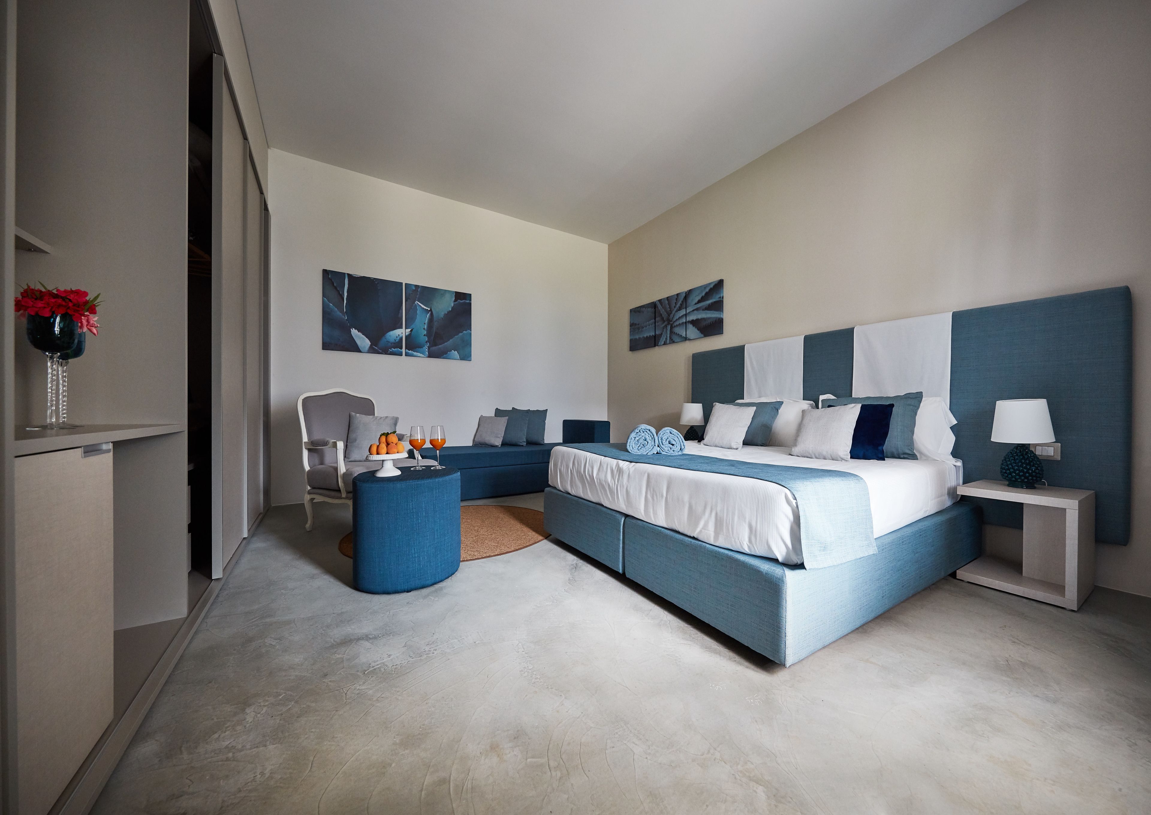 A modern bedroom with a large bed, a seating area, and artwork on the walls.