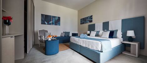 A modern bedroom with a large bed, a seating area, and artwork on the walls.