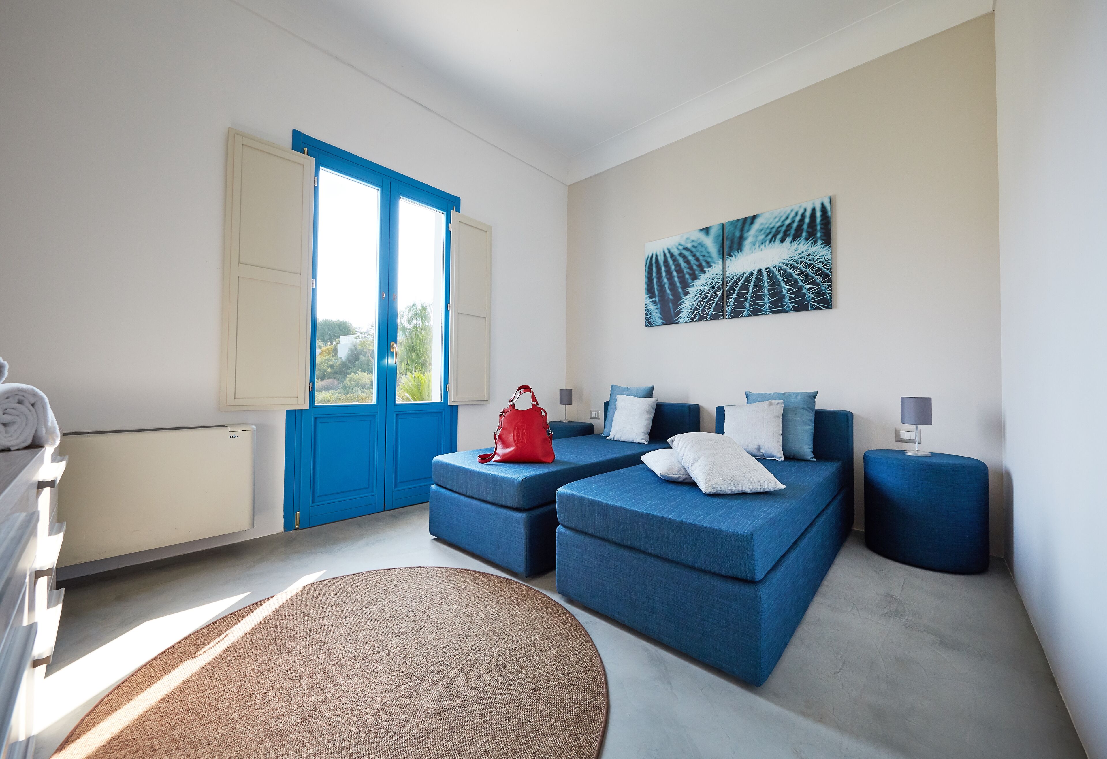 Une chambre moderne avec un canapé bleu, un sac à main rouge et un tapis rond.
