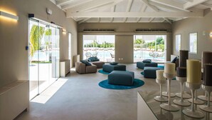 A spacious lobby with a high ceiling, large windows, and a pool view. - VOI Marsa Siclà Essentia (Scicli)