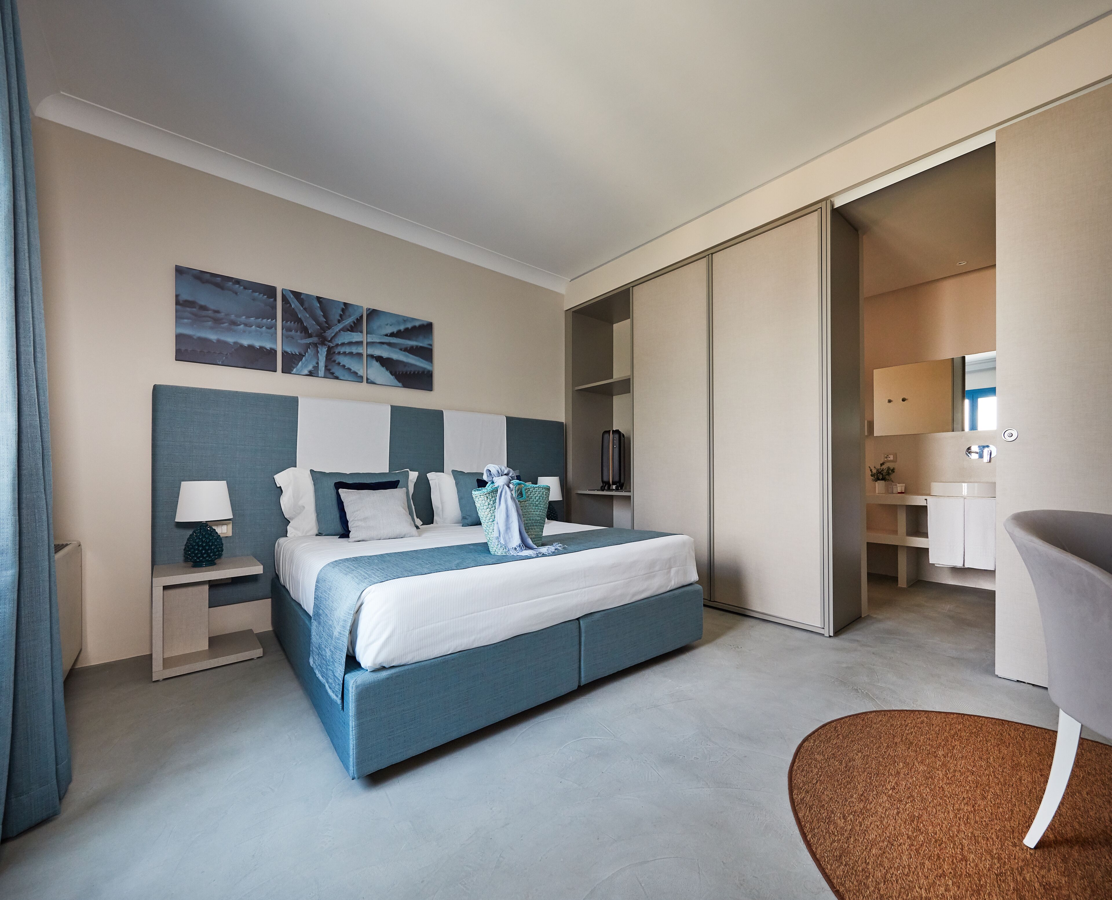 Ein modernes Hotelzimmer mit einem großen Bett, Nachttischen, einem Schreibtisch und einem durchgegangenen Tür sichtbaren Badezimmer.
