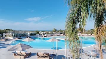 Una piscina al aire libre, sombrillas, sillones reclinables de piscina