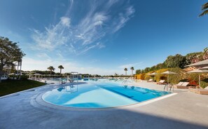 Una piscina al aire libre, sombrillas, sillones reclinables de piscina