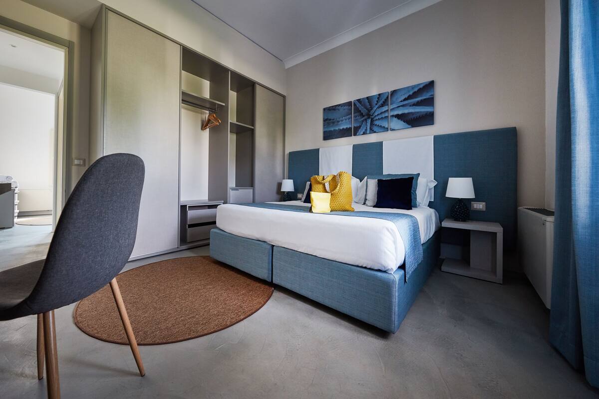 A modern hotel room with a large bed, a desk, and a chair.