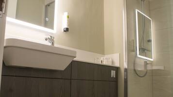 Een badkamer met een toilet, een wastafel, een spiegel en een douchecabine.