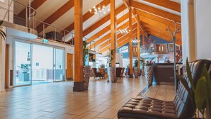 A spacious lobby with high ceilings, wooden beams, and a seating area with a leather couch. - Draycote Hotel and Whitefields Golf Club (Rugby)