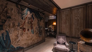 Una habitación con un mural grande, un sillón antiguo, un aparador de madera y un tocadiscos.