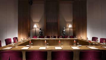 A conference room with a long table, chairs, water bottles, and lamps.
