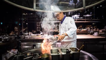 A chef cooking with a large flame on a stove in a professional kitchen.