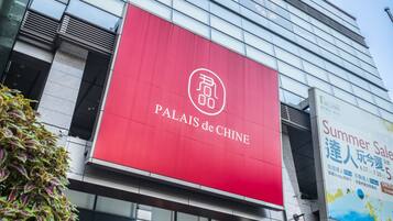 A modern building with a prominent red sign for "Palais de Chine" and a large advertisement for a summer sale.