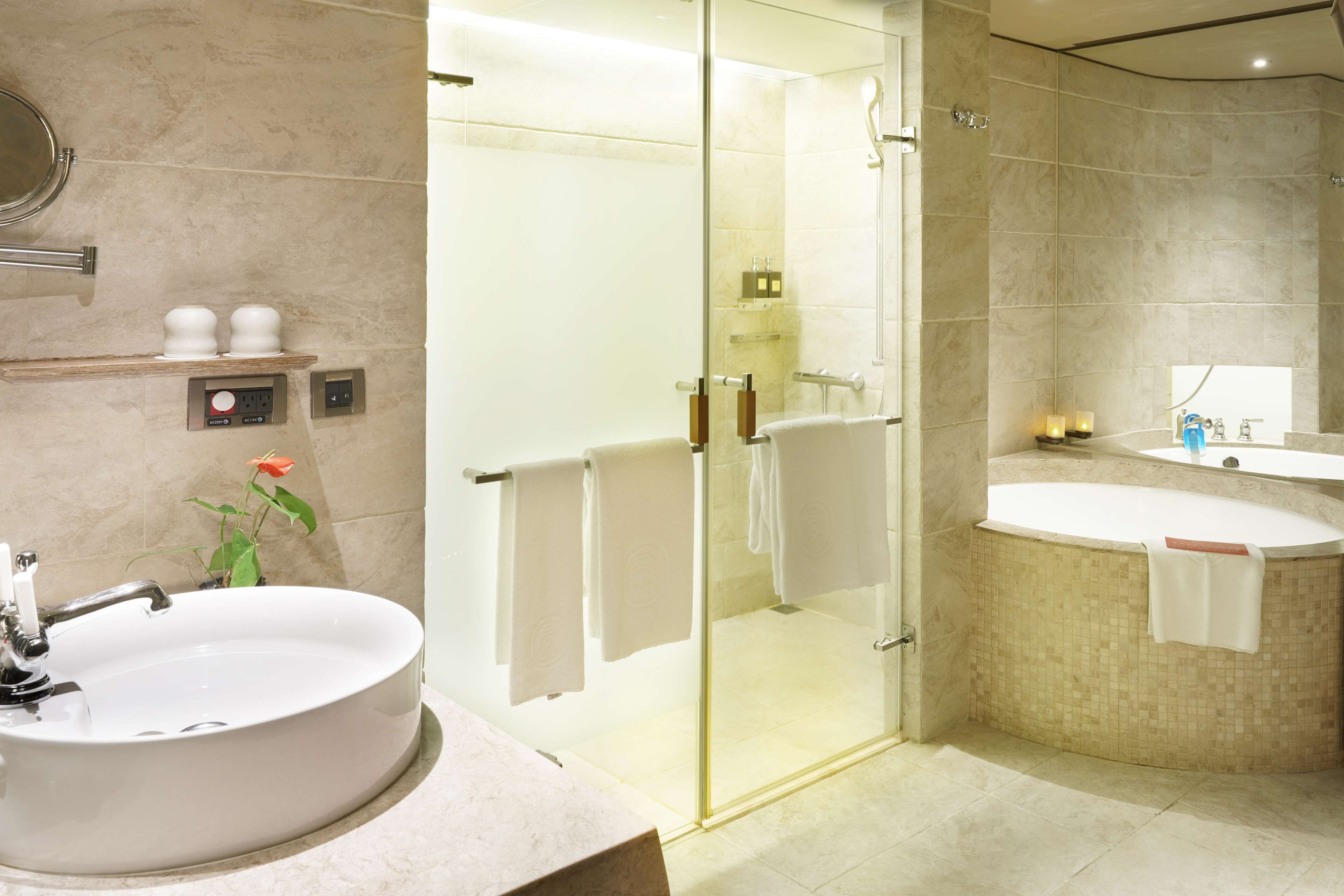 A modern bathroom with a round sink, a glass-enclosed shower, and a bathtub.