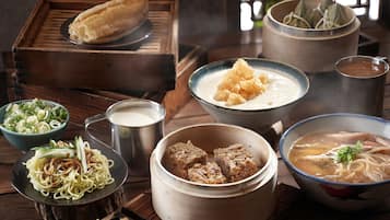 A variety of traditional dishes, including a bowl of soup, a plate of noodles, and several other dishes in a wooden tray.
