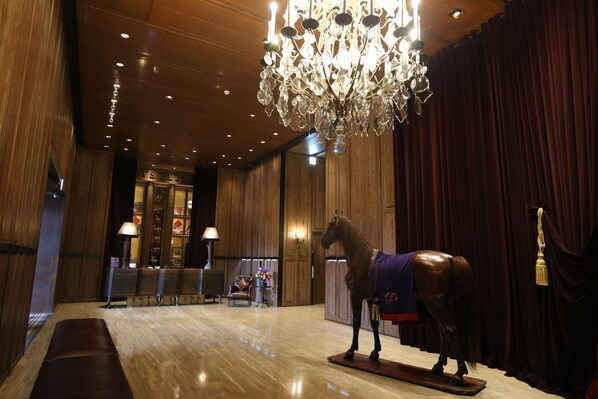 A lobby with a wooden floor, a chandelier, a horse statue, and a reception desk. - Palais de Chine Hotel (Taipei)