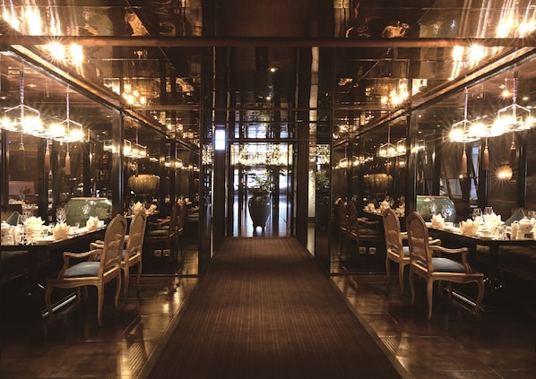 Un restaurante con un paseo central, mesas dispuestas con manteles blancos y candelabros.