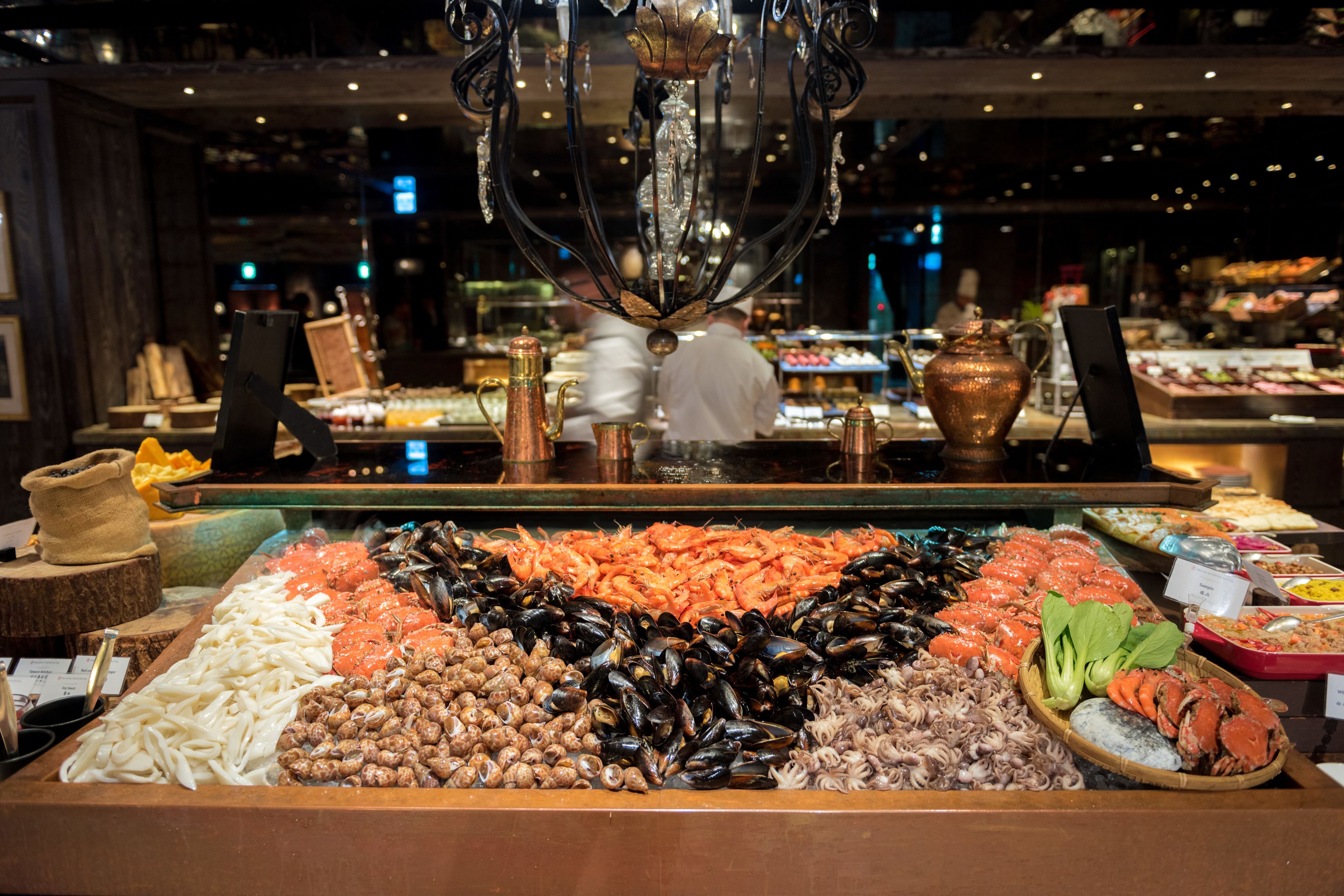 A seafood display with various types of seafood, including shrimp, mussels, and oysters, arranged in a large, open-fronted case.