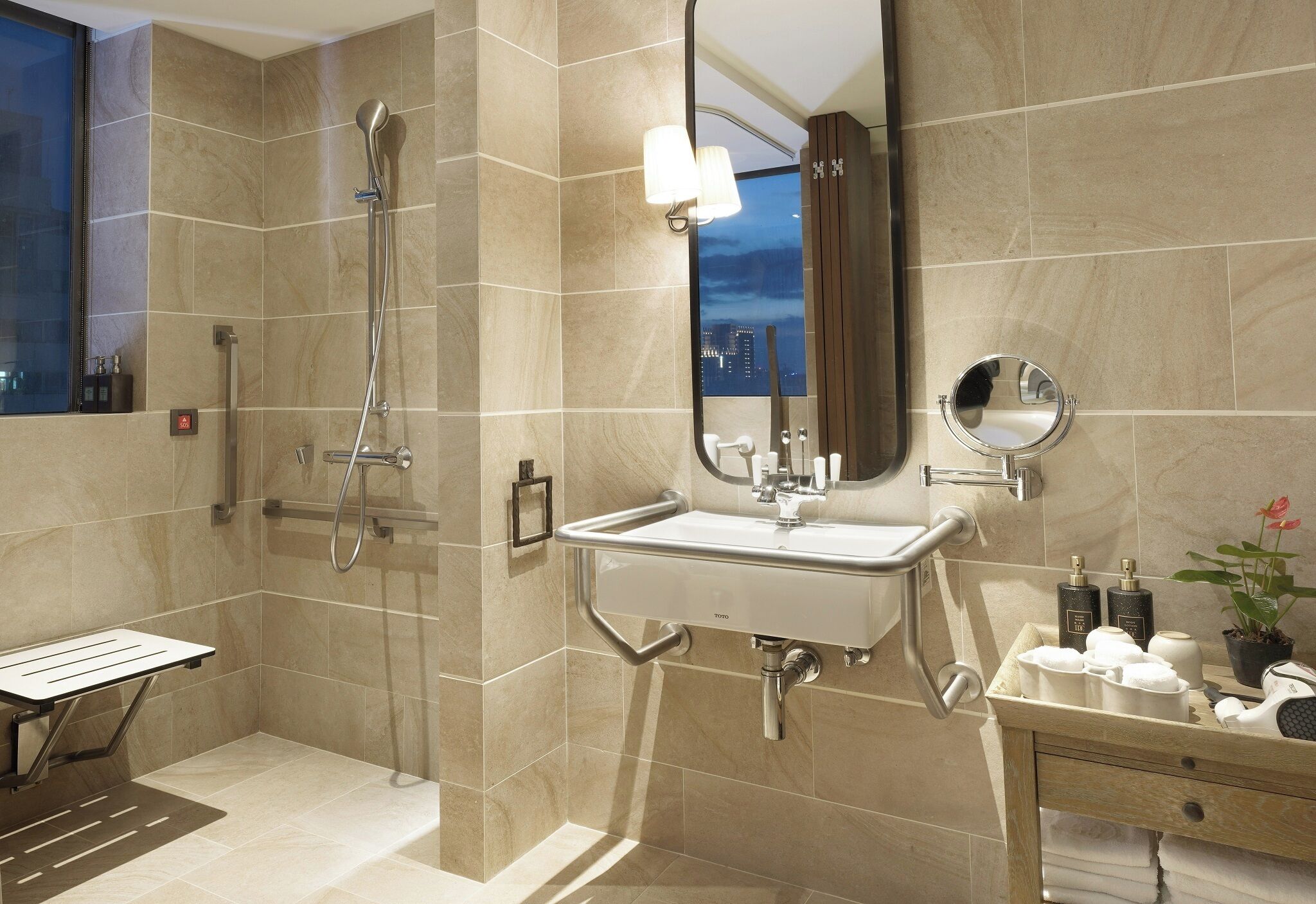 A modern bathroom with a walk-in shower, a sink with a mirror, and a vanity with toiletries.