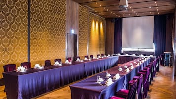 Ein Konferenzraum mit einem langen Tisch, Stühlen und einer Projektionsleinwand.