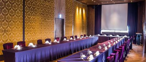 A conference room with a long table, chairs, and a projector screen.