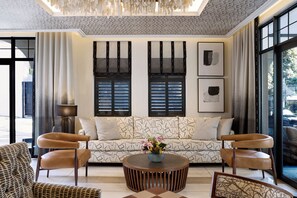 A modern living room with a patterned sofa, two armchairs, a coffee table, and a large window with blinds. - Park Hyatt Johannesburg (Johannesburg)