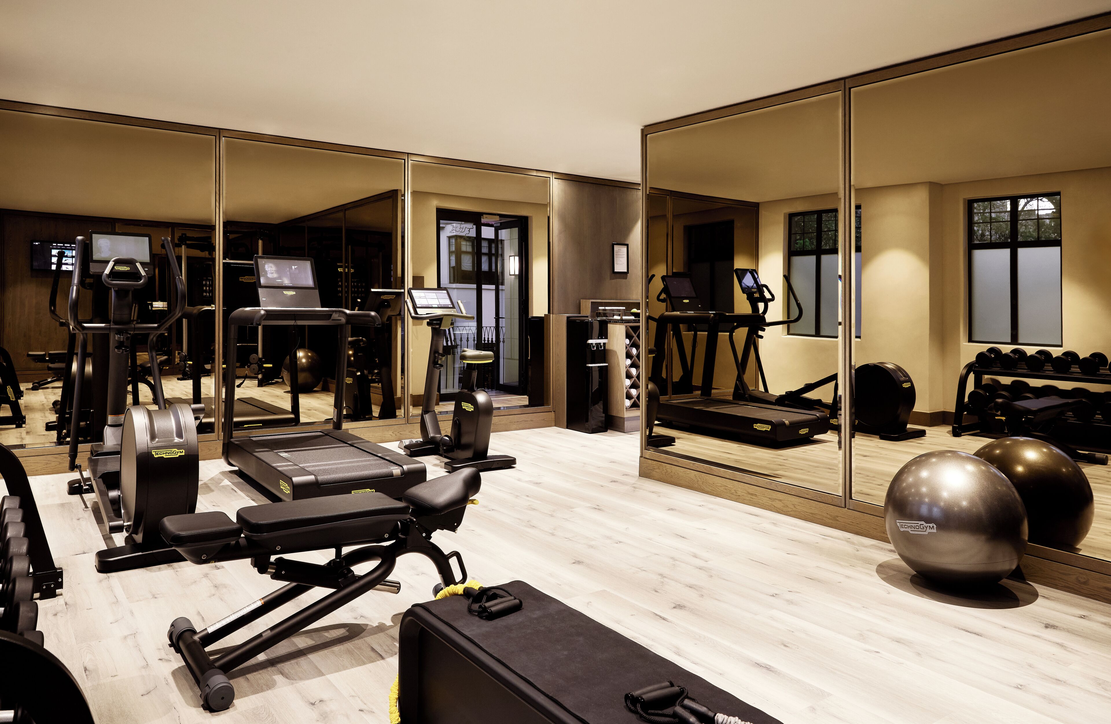 Un gimnasio con diversos equipos de ejercicio, como cintas de correr, pesas y pelotas de entrenamiento.