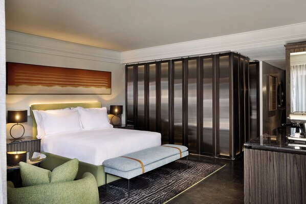 Habitación de hotel con una cama grande, un banco, un escritorio y un armario.