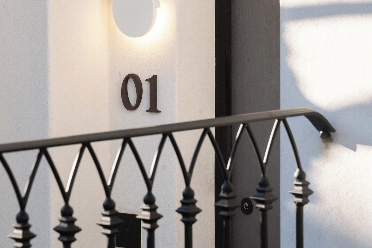 Une rambarde de balcon en métal avec une plaque portant le numéro « 01 » sur un mur blanc.