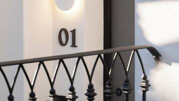 Une rambarde de balcon en métal avec une plaque portant le numéro « 01 » sur un mur blanc.
