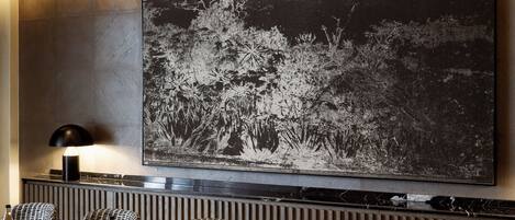 Un salón de conferencias con una gran mesa, sillas de mimbre, un candelabro moderno y una obra de arte grande en blanco y negro en la pared.