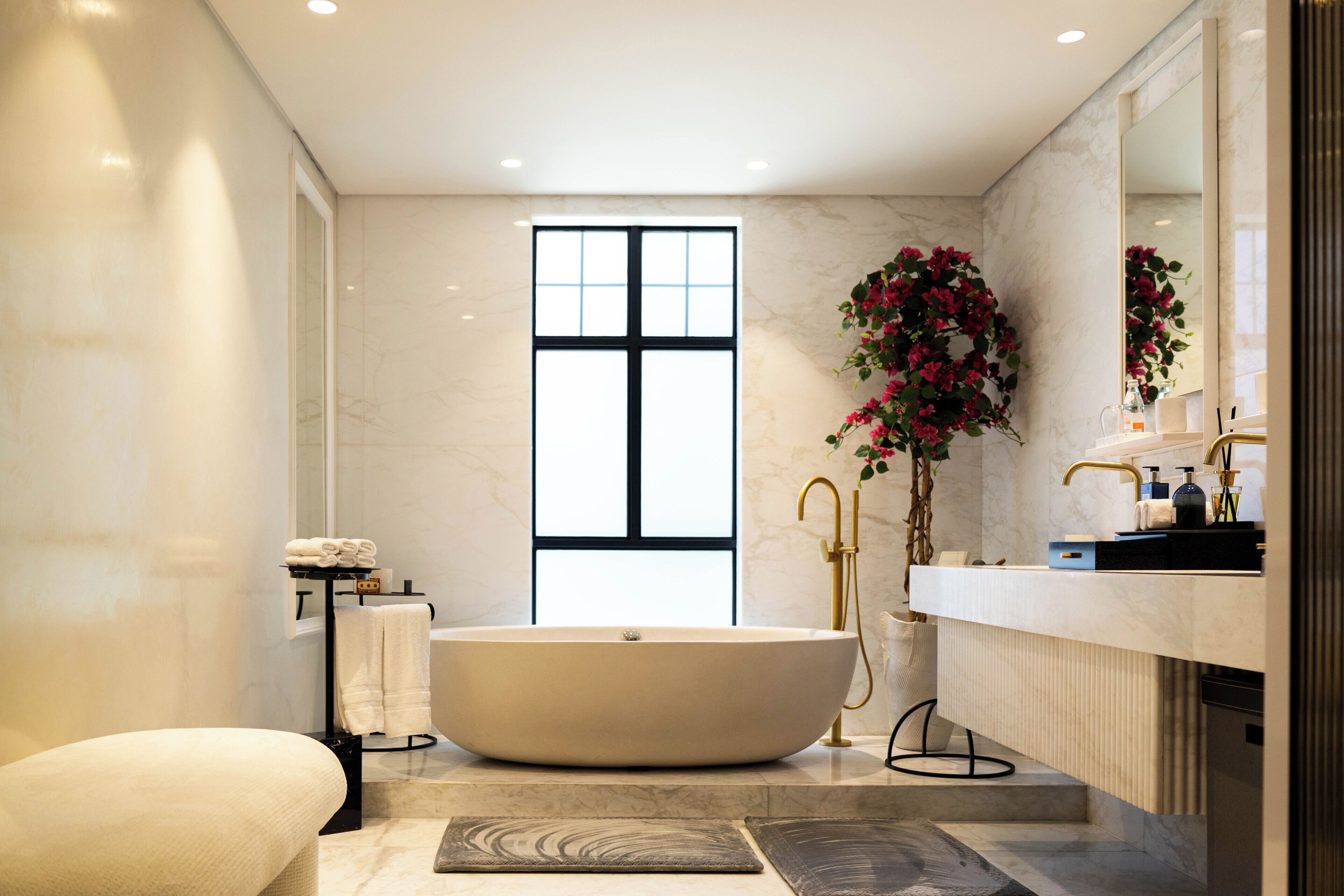Ein modernes Badezimmer mit einer freistehenden Badewanne, einem großen Spiegel und einem Fenster, das für natürliches Licht sorgt.