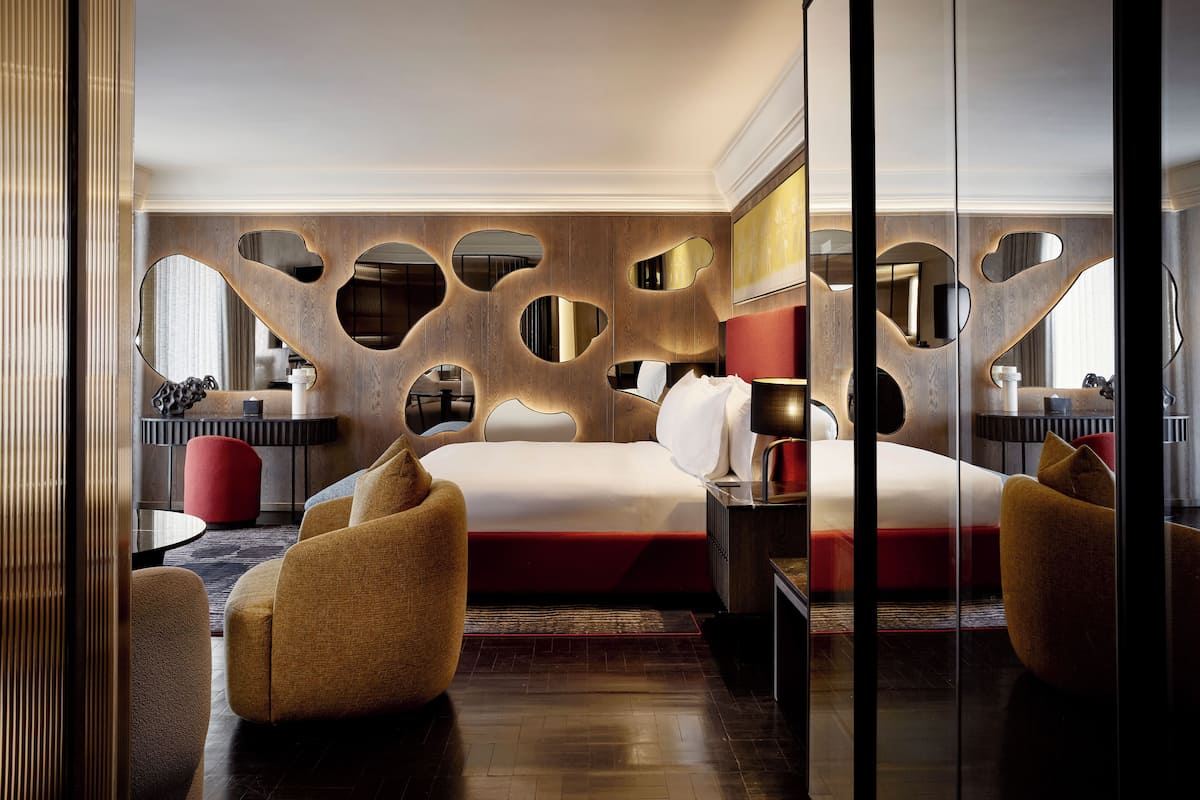 Une chambre d’hôtel moderne dotée d’un grand lit, d’un coin salon et d’une coiffeuse avec un miroir.