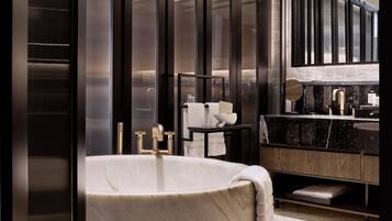 A modern bathroom with a large bathtub, a vanity with a marble countertop, and a large mirror above the sink.