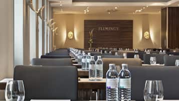 A hotel dining area with tables set for guests, water bottles, and glasses on each table.