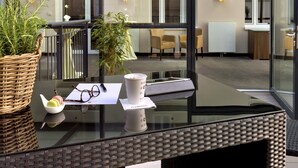 Un interior moderno con mobiliario de mimbre, una mesa de vidrio y vistas al exterior.