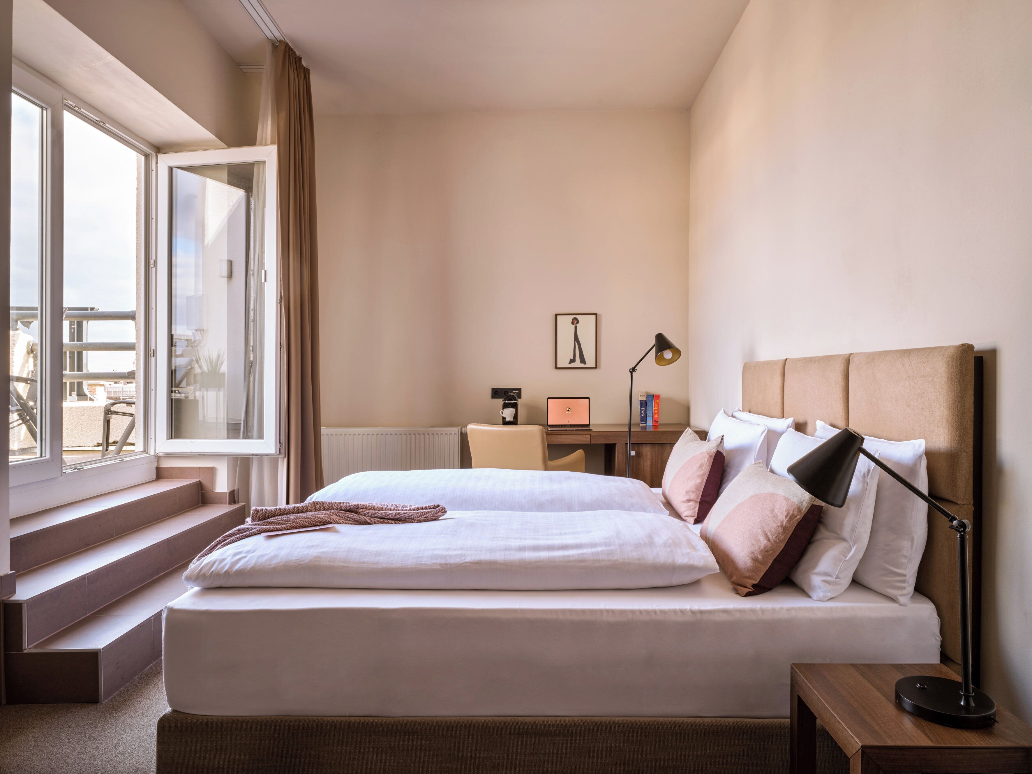 Habitación de hotel con una cama grande, un escritorio con una computadora portátil y vistas al exterior.