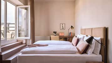 Habitación de hotel con una cama grande, un escritorio con una computadora portátil y vistas al exterior.