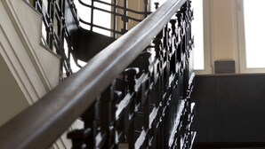 Una escalera con barandilla negra y una lámpara de techo texturizada y original.