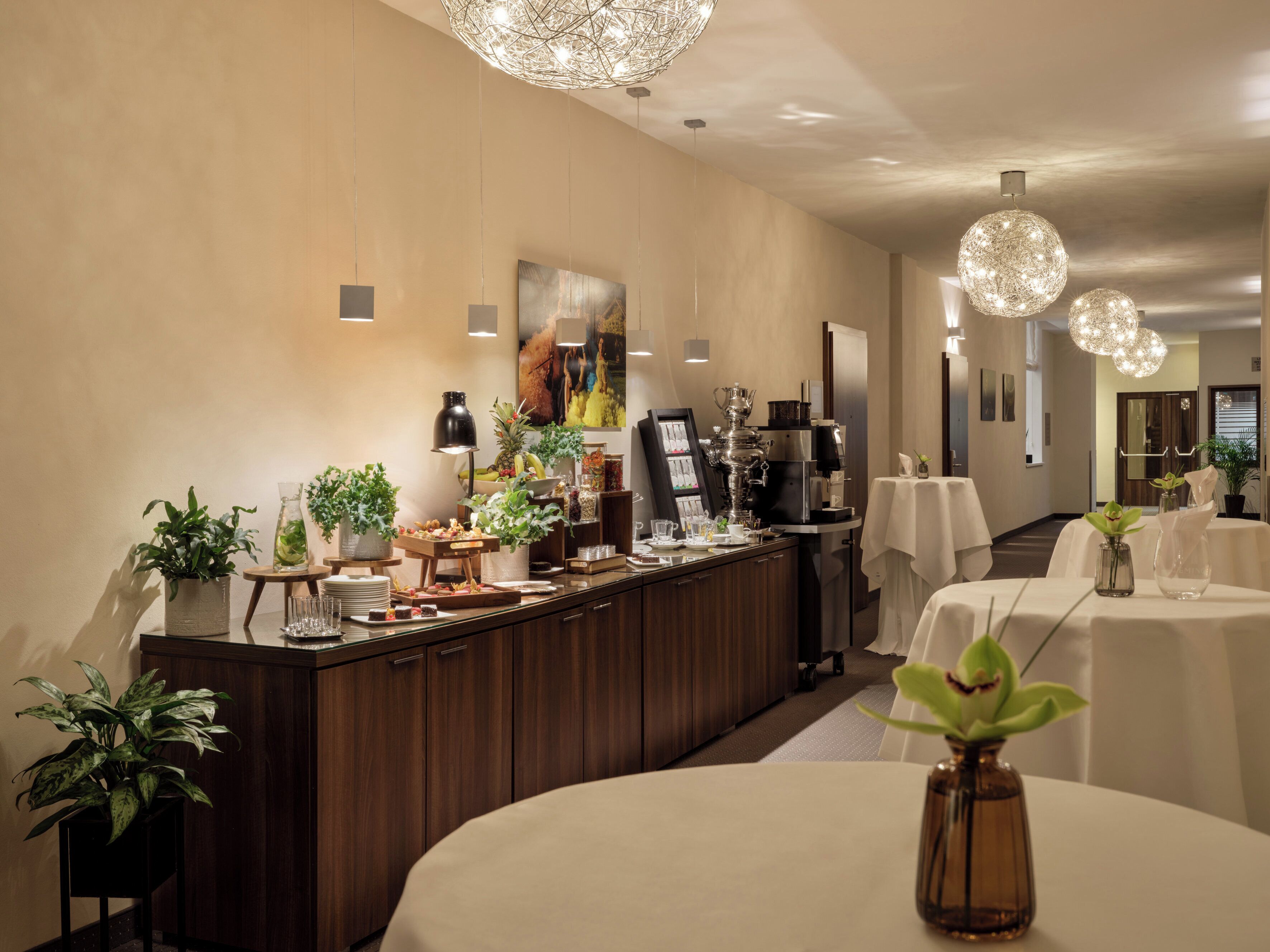 Ein Hotel-Rezeptionsbereich mit Buffet, Kaffeeautomat und einem großen Gemälde an der Wand.