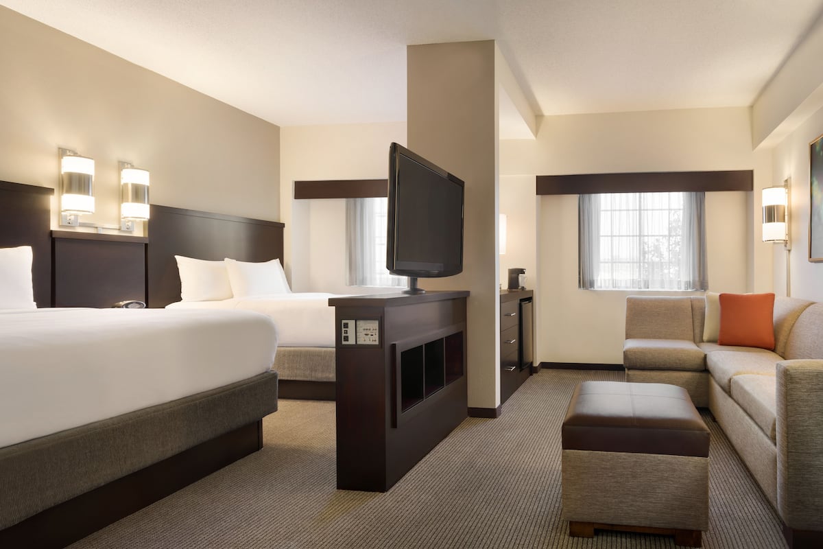 A hotel room with a large bed, a TV, a sofa, and a desk.