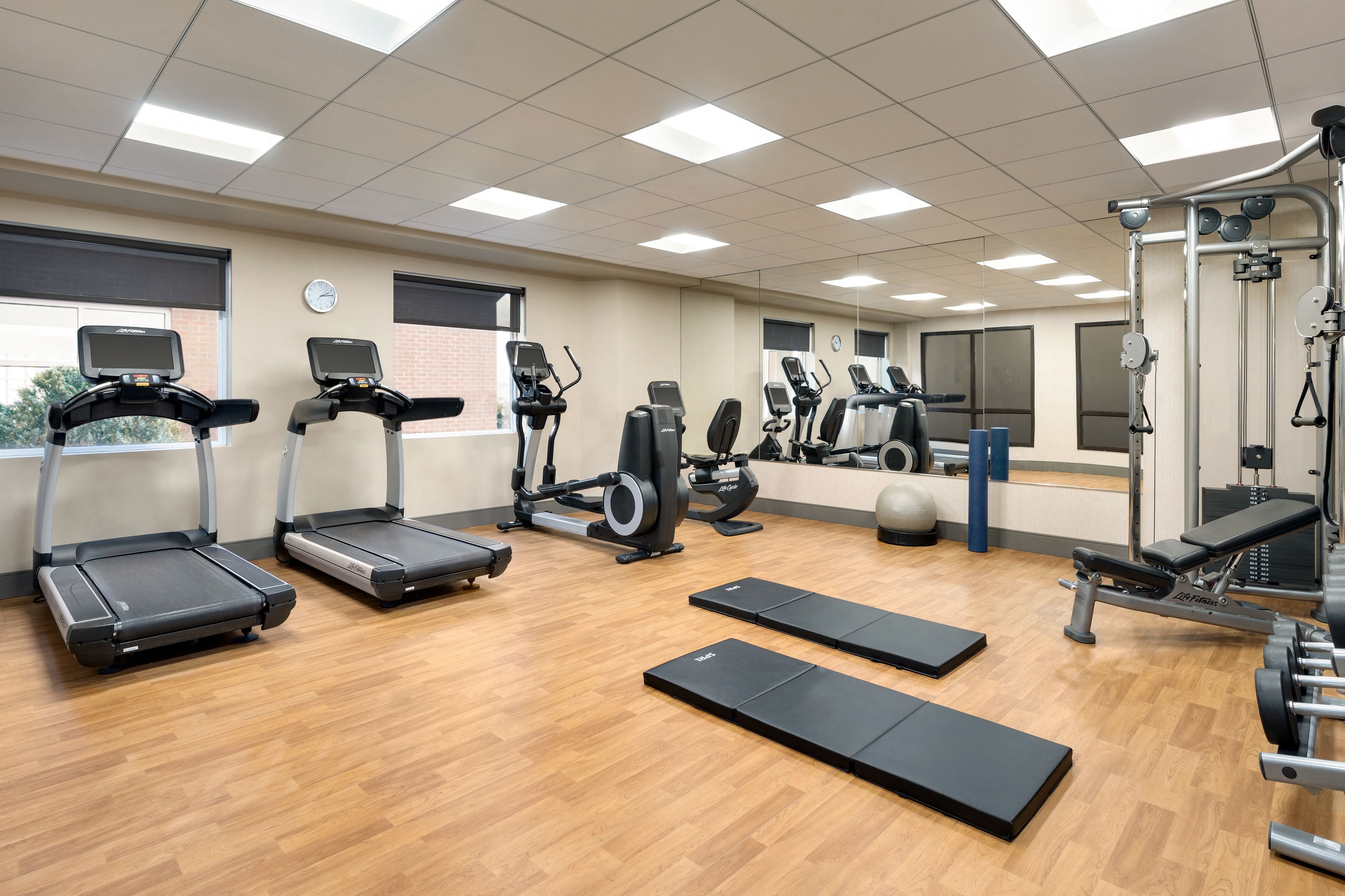 Une salle de sport équipée de tapis de course, de vélos elliptiques et de poids libres.