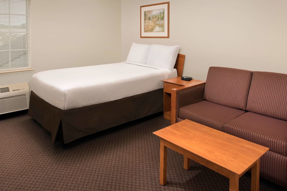 Une chambre d’hôtel avec un lit, un canapé, une petite table et un tableau au mur.